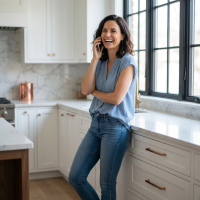 Woman leaning against a counter, talking on the phone and laughing.