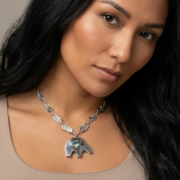 A native American woman wearing a silver pendant with a detailed chain. The focus is on the pendant